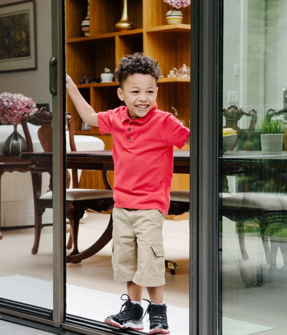 Young boy in the opening of an easy-to-use screen door.