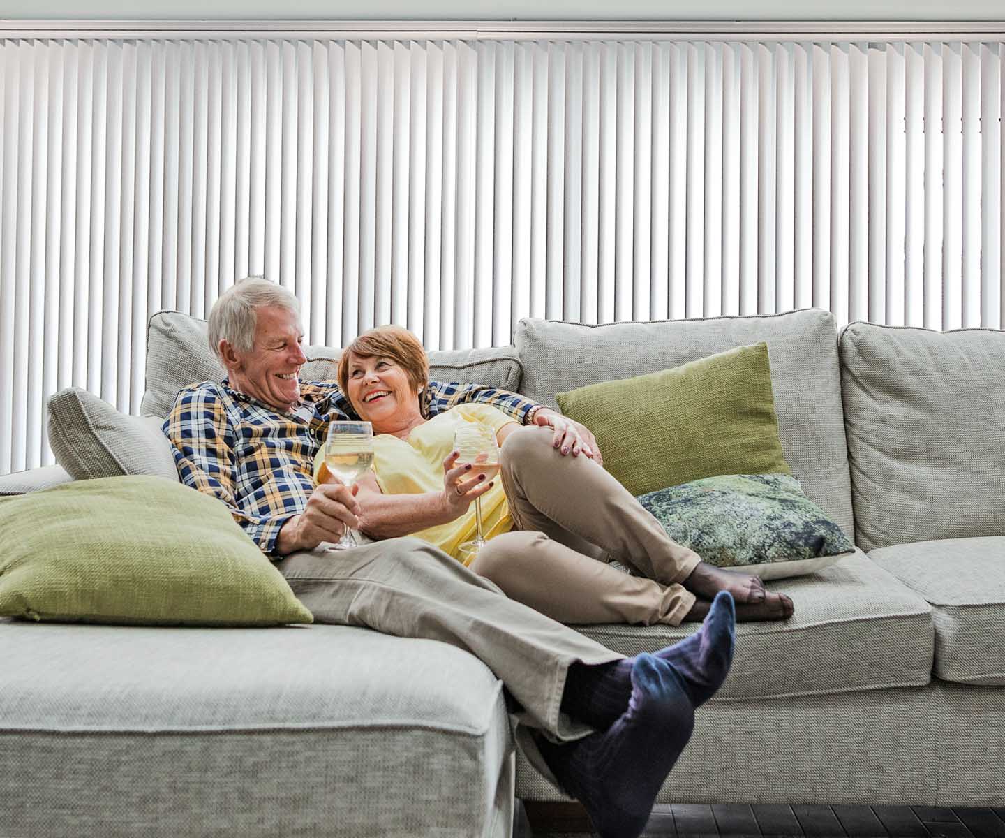 A couple enjoying a glass of wine in a cozy living room with Synchrony Vertical Blinds located in McLean, VA